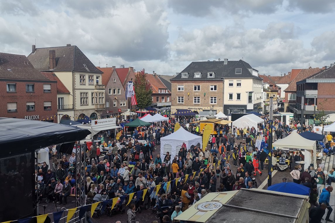 Das Bild zeigt den Marktplatz mit Ständen, Bühne und viel Publikum.