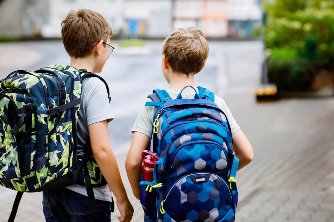 Das Bild zeigt zwei Schulkinder von hinten mit ihrem Tornister.